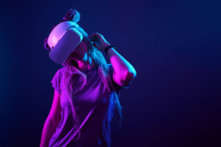 这位女士正在使用虚拟现实耳机。霓虹灯工作室肖像。