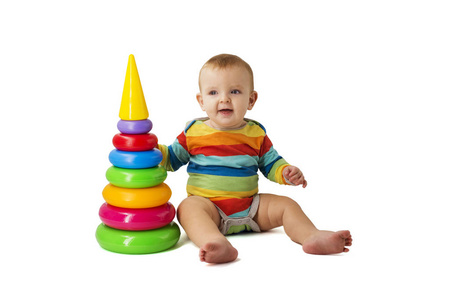 可爱可爱的婴儿穿着工作服，在白色背景上玩彩色塑料金字塔。一个孩子收集一个彩色金字塔