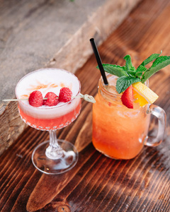 Two alcoholic cocktails garnished with berries and mint 