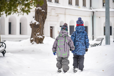 两个小男孩穿着五颜六色的衣服，在户外滑雪