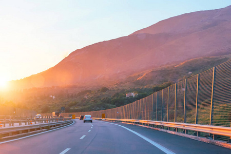 高速公路和转弯的背景是山脉和日落。