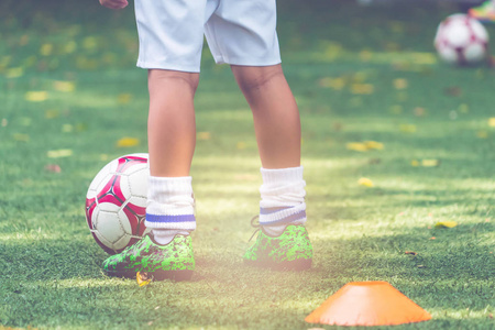 小男孩正站在足球场上，脚上挂着足球