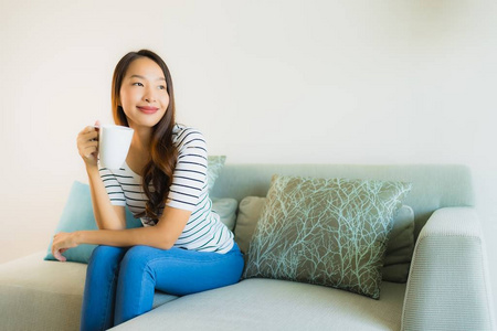 咖啡杯沙发上美丽的亚洲年轻女子肖像