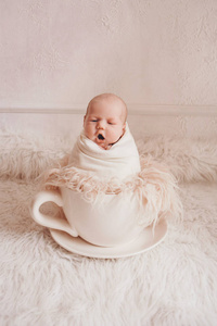 新生婴儿在一个大茶杯里。儿童概念，健康，试管婴儿，热饮，早餐