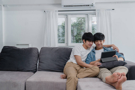 亚洲lgbtq 男士在客厅躺在沙发上,一边在互联网上一起看电影,一边享受