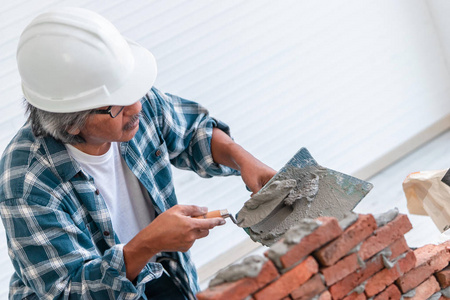 高级建筑工人正在用水泥砌砖墙