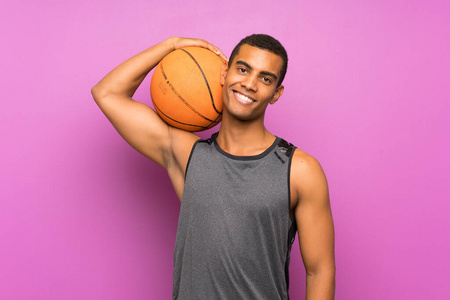 一个年轻的体育运动员，在孤立的紫色墙上打篮球