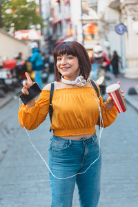 美丽的女孩站在街上听音乐