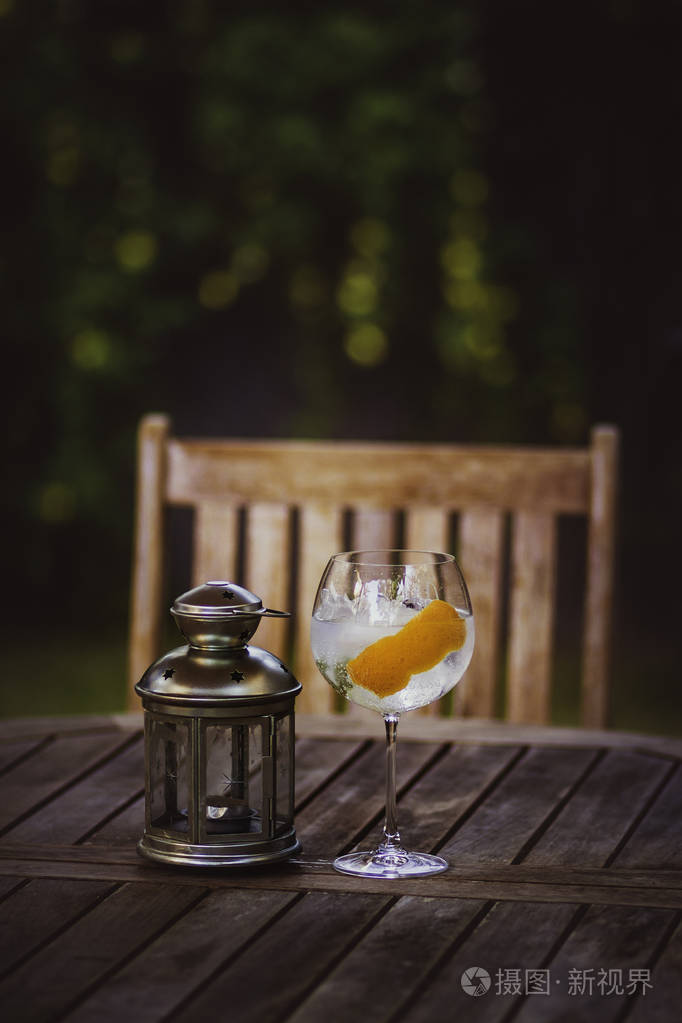 一杯杜松子酒和金属灯放在花园的木桌上照片-正版商用图片260q9l-摄图