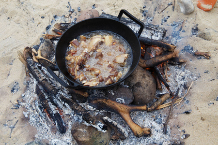 Pieces of lamb are fried in boiling oil in a pan on the fire. 