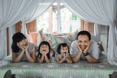 亚洲快乐家庭和在床上放松的小女儿
