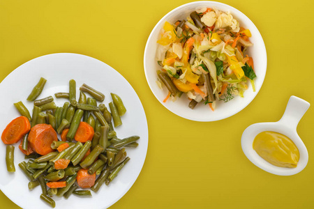  Green beans with garlic carrots on a white plate on a colored b