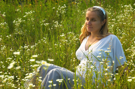 年轻的孕妇，坐在花丛里，春天