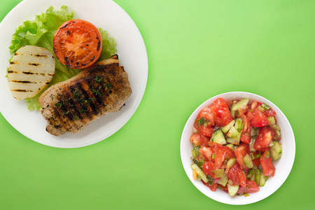  grilled pork with potatoes and tomatoes on a colored background