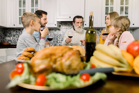 多代同堂的家庭庆祝感恩节，坐在喜庆的餐桌上烤火鸡和美味的菜肴
