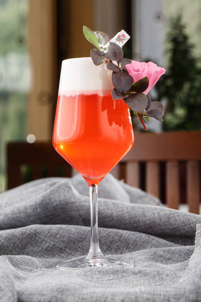 酒杯配覆盆子鸡尾酒配覆盆子酒精,灰色背景上有花朵.俯视图,复印空间.