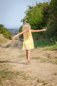 快乐的孩子穿着黄衣在乡间小路上跳舞
