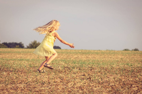 spontaneous child in yellow dress dancing wildly in rural path 