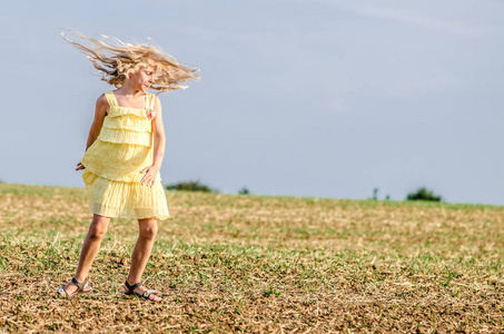 spontaneous child in yellow dress dancing wildly in rural path 