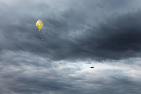 黄色气球飘向多云的天空