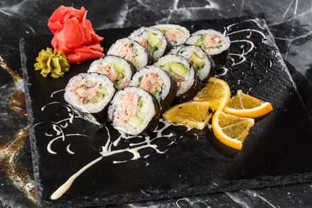寿司卷内有三文鱼鳄梨金枪鱼和黄瓜。黑大理石背景三文鱼寿司卷。寿司菜单。日本菜。水平照片。