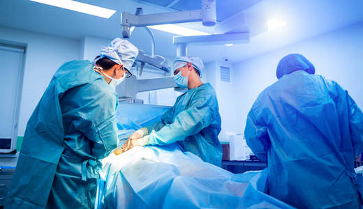一群医生给病人做手术。外科医生穿着军装，戴着口罩在手术室工作。