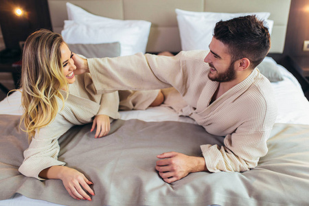 一对穿着浴袍的夫妇躺在旅馆房间的床上。