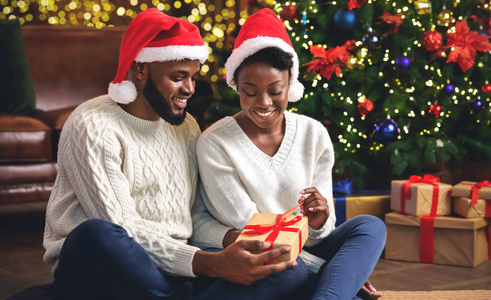 黑人夫妇在家庆祝圣诞节，一起拆开礼物