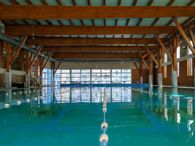 一个大的室内游泳池，里面满是水，里面没有人，可以进行游泳的健康娱乐活动