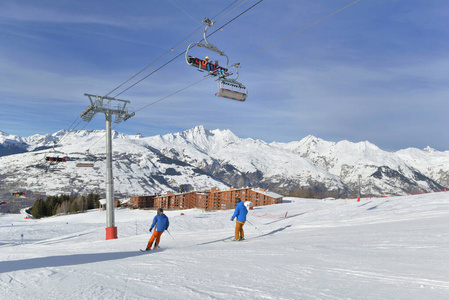 skiers on slopes and chairlifts in alpine resort 