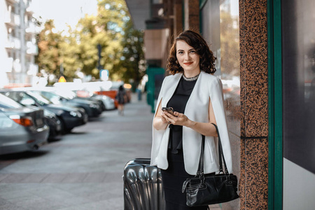 在大城市里带着手提箱的时髦女孩.商务假期.出差.华沙照片