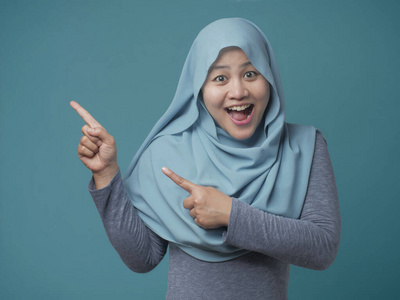 迷人的穆斯林妇女微笑着指着旁边