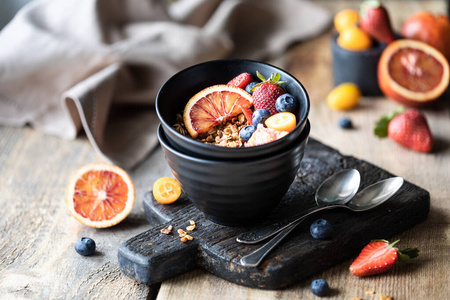 早餐自制格兰诺拉麦片配新鲜浆果，水果。健康饮食的概念。木桌。深色背景