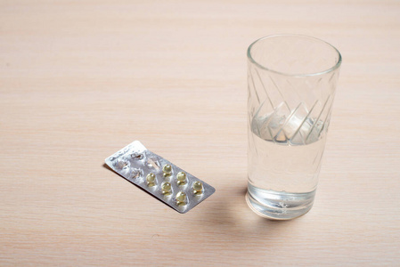 用药片和一杯水泡在明亮的桌子上
