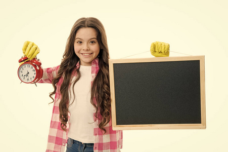 上课时间到了。快乐的小女孩拿着空白的黑板和闹钟。时间概念。实行良好的课时管理。完美的时间准确性，复制空间