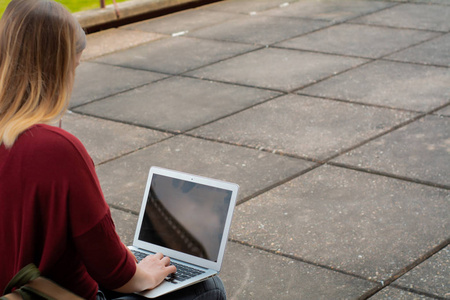 Young student using laptop outdoors. 