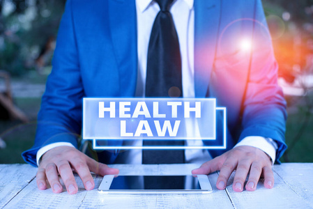 写便条显示卫生法。商业照片展示法律，提供法律指导，为医疗保健商人提供蓝色套房，系领带，手拿笔记本电脑。