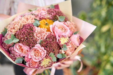 欧洲花店。一束美丽的混合花在女人手中。花店里花匠的工作。送鲜切花。