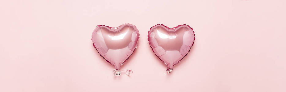 两个粉红色的气球，在粉红色的背景上做成一个心形。概念情人节，婚礼装饰。锡箔球。横幅。平放，俯视图