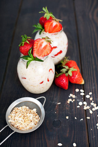 Oatmeal with yogurt and strawberries on a dark wooden background