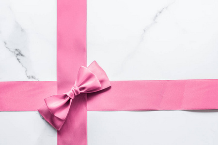 Pink silk ribbon and bow on marble background, girl baby shower 