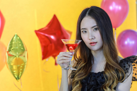 笑容可掬的亚洲年轻女子手持红酒的画像