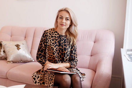 Beautiful thoughtful young woman siting on the sofa and looking 