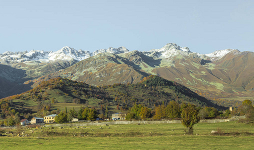 一个小山村和雪峰的全景，在远处可见，在乔治亚州的山区斯瓦内提日落