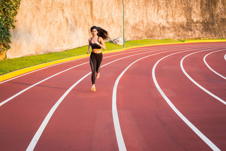 在田径跑道上赛跑的年轻女子赛跑运动员照片