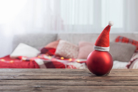 red Christmas ball on old wooden table on background sofa 