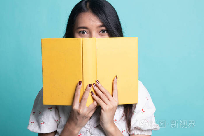 一位年轻的亚洲妇女拿着一本书遮住了她的脸