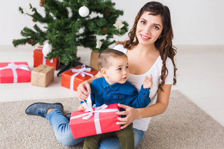 圣诞节，单亲家庭和假日概念可爱的小男孩拿着圣诞礼物给他的母亲在家。
