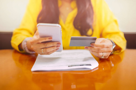 女商人使用手机银行应用程序在家里付账。