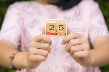 女性手中的木制日历，日期为12月25日